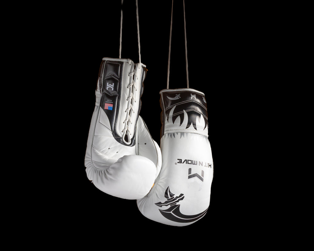 White and black HIT'N'MOVE VECTOR boxing gloves with flame graphics hanging by white laces against a black background