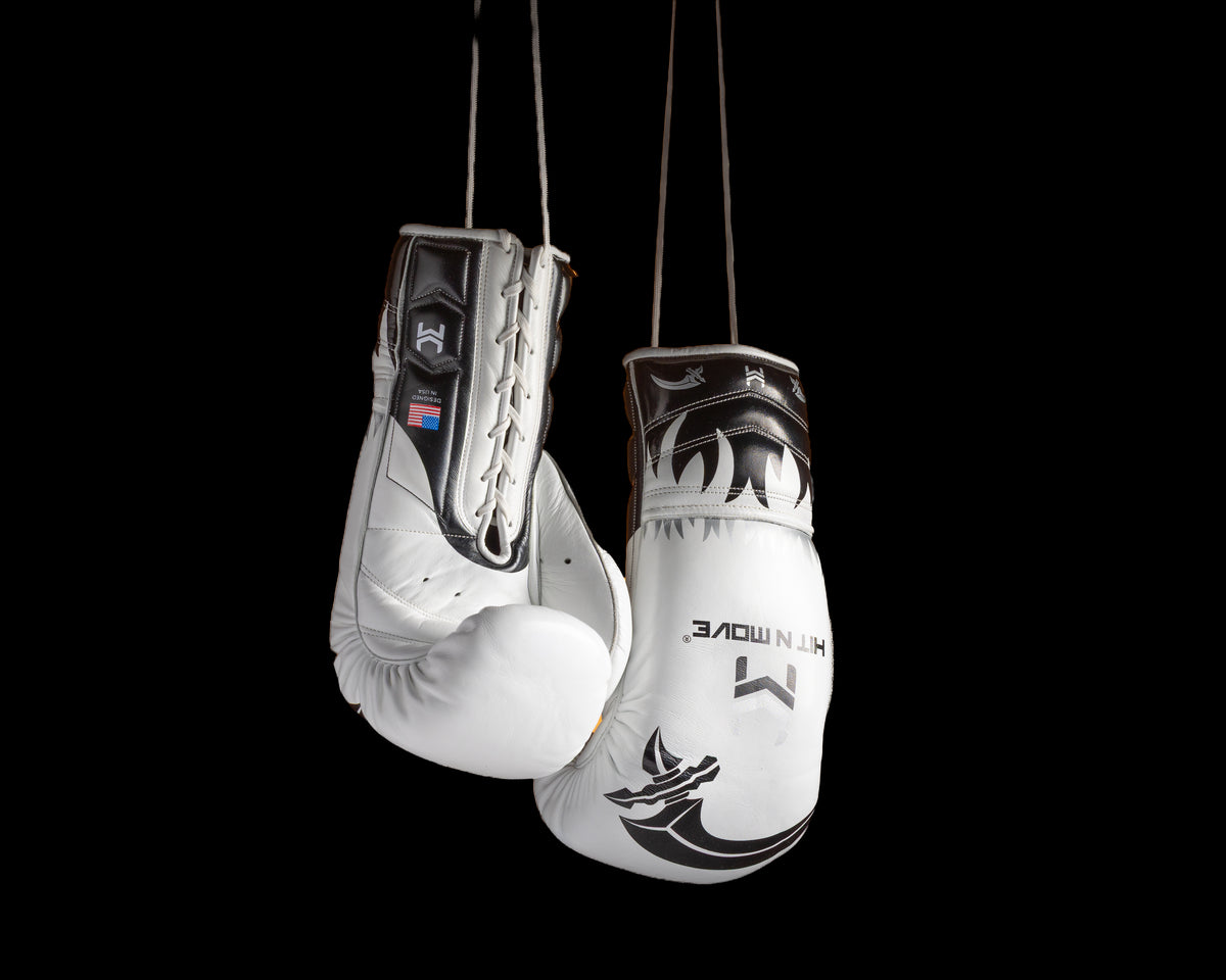 White and black HIT'N'MOVE VECTOR boxing gloves with flame graphics hanging by white laces against a black background