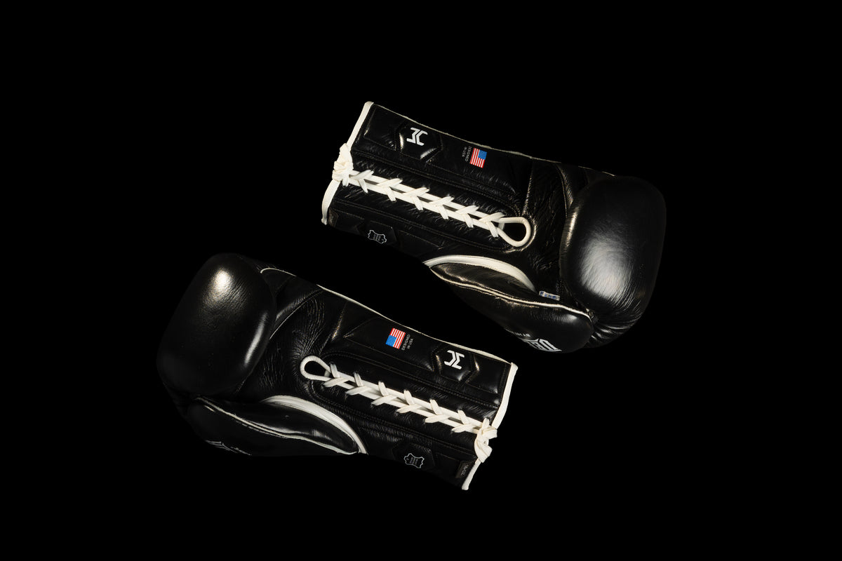 Black HIT'N'MOVE VECTOR boxing gloves on a black background, showing white laces, palm sides and thumb padding