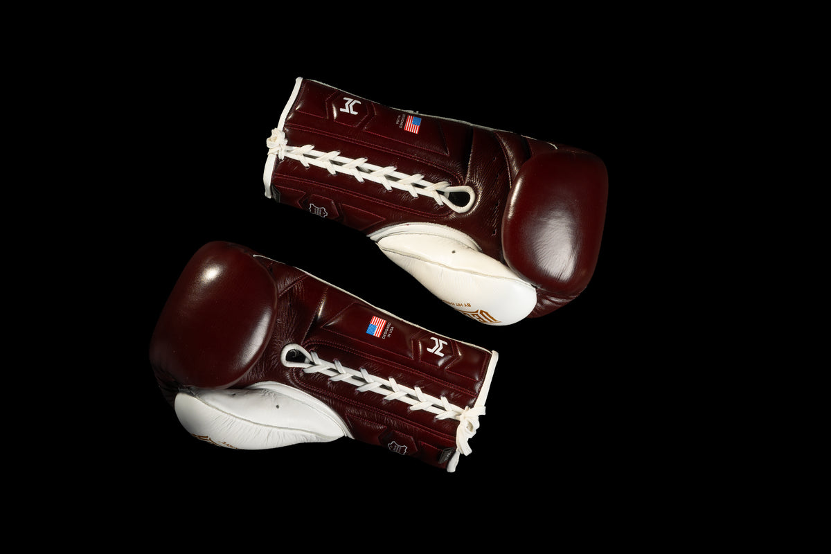 Burgundy and white HIT'N'MOVE VECTOR boxing gloves on a black background, showing white laces and palm sides