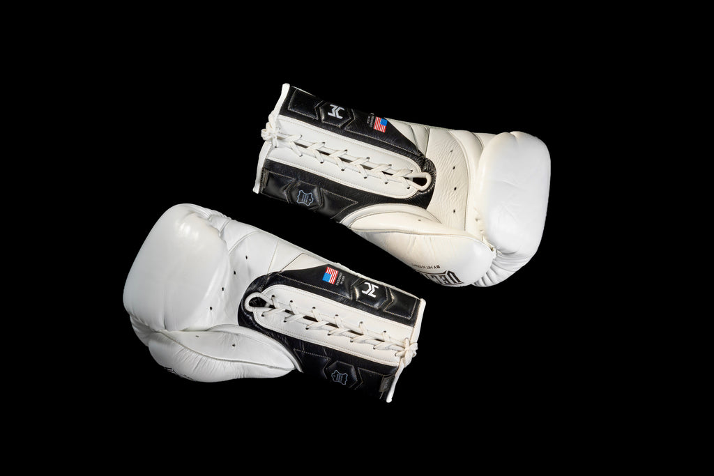 White and black HIT'N'MOVE VECTOR boxing gloves on a black background, showing white laces and palm sides