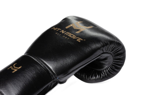 Close-up of a black HIT'N'MOVE 24 oz conditioning boxing glove showing gold logo and padded knuckle area